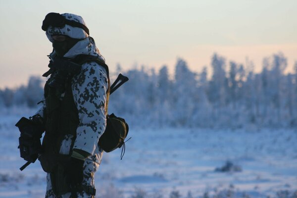 Uomo in mimetica sullo sfondo di un paesaggio invernale