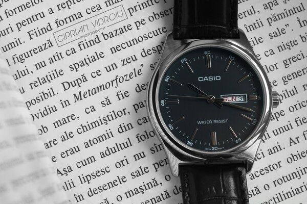 Orologio con quadrante nero appoggiato su un libro