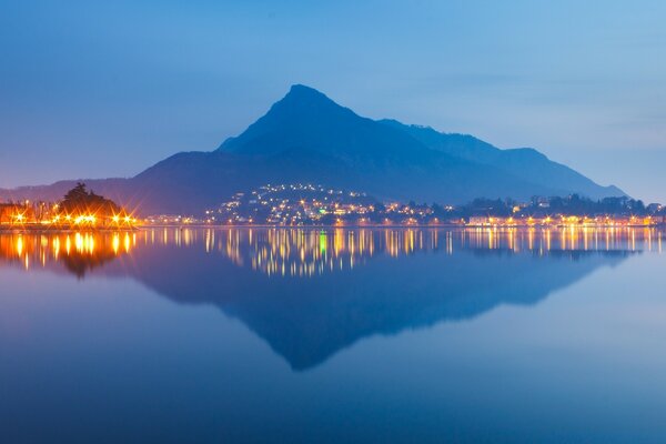 Riflesso della montagna e delle luci della città nell acqua