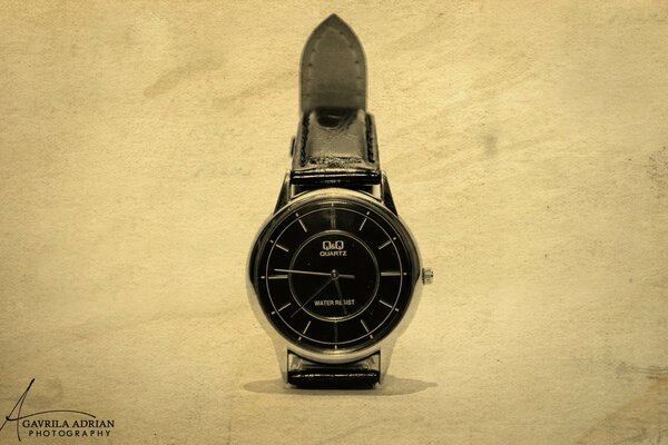 Orologio con quadrante nero e cinturino su sfondo chiaro