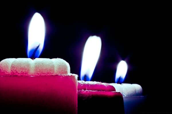 Fiamma di candele colorate su sfondo scuro