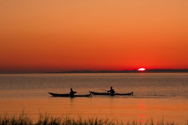 La gente galleggia sulle barche durante il tramonto
